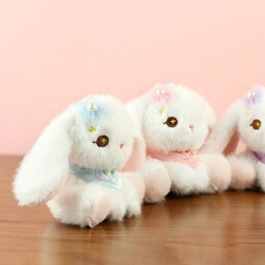 Dettaglio di portachiavi a coniglietto in peluche con fiori e sciarpe ricamate