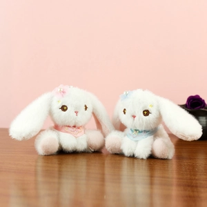 Dettagli dei ciondoli a coniglietto di peluche bianco con sciarpe e occhi stellati ricamati