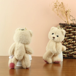 Detail of beige teddy bear plush keychain with metal ring and Happy Day label