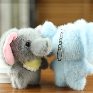 Detail of plush elephant keychains in grey and blue with soft fur on a wooden table