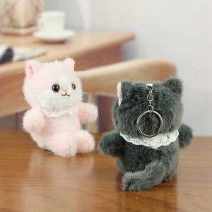 Close-up of pink and grey plush cat keychains with lace collars and soft faux fur detail