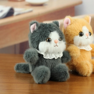 Close-up of grey and orange plush kittens with lace collars on a wooden surface