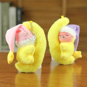 Gros plan de pendentifs lune en peluche jaune avec visages brodés et bonnets de nuit doux