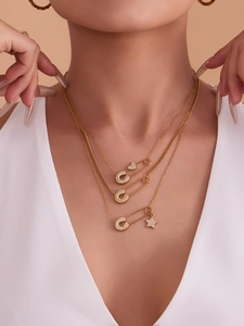Dettaglio della collana a graffetta dorata con pendenti a stella e cuore scintillanti