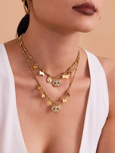 Close-up of a double-layer golden puppy necklace with heart and bone charms and hoop earrings