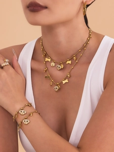 Detailed view of dog bone, paw, and skull charms on a gold-plated zircon jewelry set