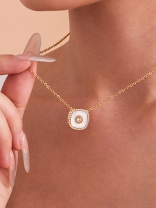 Gros plan du pendentif trèfle plaqué or 18k avec détails en nacre et en zircon