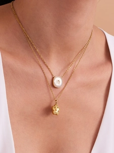 Détail de colliers superposés dorés avec pendentif nacre et breloque fleurie