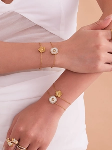 Détail d'un ensemble de bijoux fleurs plaqué or 18k et perles porté sur un bras de femme