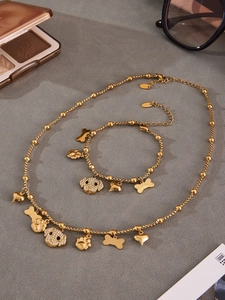Detail of gold puppy jewelry set with zircon pave heart and bone charms on gray surface