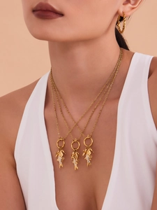 Gros plan d'un collier doré à plusieurs rangs avec pendentifs hippocampe et accents blancs