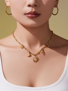 Détail des pendentifs soleil, lune et étoile sur un collier à perles dorées porté par un mannequin