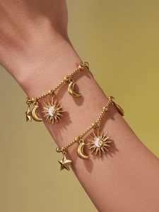 Détail d'un bracelet à billes doré orné de breloques célestes telles que soleil, lune et étoile