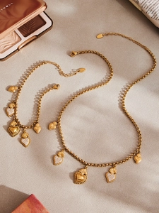 Détail d'une parure de bijoux dorés lune et soleil avec breloques en forme de cœur