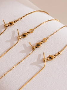 Dettaglio di quattro catene in acciaio placcato oro 18k con chiusure e sfere regolabili