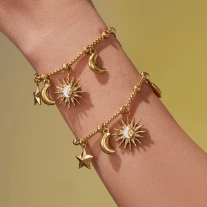Bracelets célestes dorés avec breloques soleil et lune et chaînes perlées sur un poignet