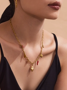 Detail of a gold chain necklace with red enamel chili peppers and heart pendants