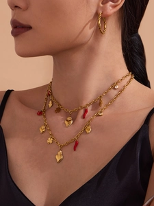 Detailed close-up of a gold double-layer necklace with red chili and heart charms