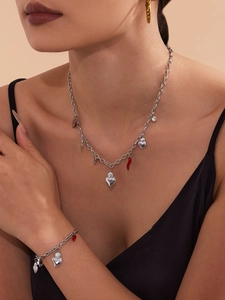 Detail of a stainless steel heart and chili charm necklace and bracelet set on a model