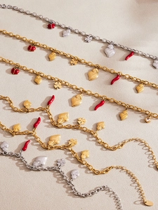 Macro view of stainless steel charm bracelet with red chili, ladybug and heart pendants