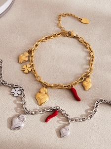 Close-up of gold and silver stainless steel bracelets with heart and chili charms