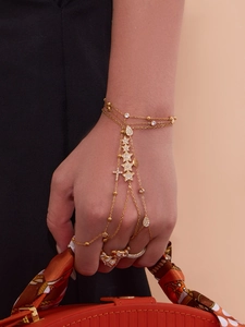 Détail d'un bracelet bague plaqué or 18 carats avec breloques étoile et croix en zircone