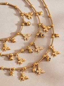 Macro-opname van gouden vlinder- en hartjeshangers met kristallen aan een kralenketting