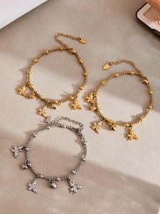 Detailopname van roestvrijstalen armbanden met vlinder- en hartbedeltjes in goud zilver