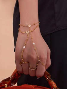 Détail d'un bracelet bague plaqué or 18k avec pendentifs cœurs et perles blanches