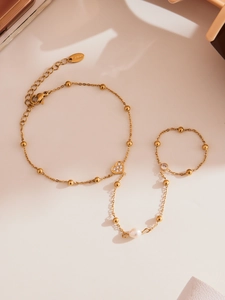 Détail macro d'un bracelet en acier doré 18 carats avec breloque cœur et perle