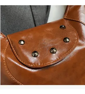 Close-up of brown PU leather bag featuring retro texture and conical metal rivets