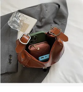 Detail showing the spacious interior of a brown vintage leather crescent bag with items inside