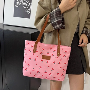 Pink cherry print tote bag with leather straps worn by model in trench coat