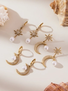 Dettaglio di orecchini boho dorati con stelle, lune, perle e pietre di zircone