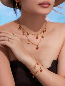 Dettaglio di collana a strati in oro 18k con ciondoli a forma di ciliegia e fragola