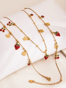 Dettaglio catena in acciaio placcato oro 18k con ciondoli colorati fragola e ciliegia