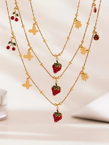 Dettaglio di parure di gioielli placcati oro 18 carati con fragole, ciliegie e coccinelle