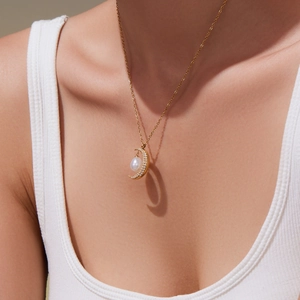 Collana con pendente a luna dorata con zirconi e perla indossata da una modella