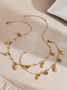 Détail du collier en acier doré avec pendentifs éléphants et petites clochettes rondes