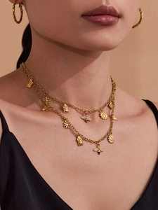 Detail van gelaagde gouden ketting met bijenhangers en getextureerde ronde oorringen