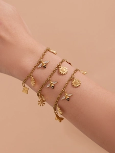 Detailopname van een gouden roestvrijstalen armband met bijen- en zonnebloembedels