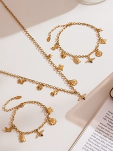 Detail van de gouden roestvrijstalen ketting met bedels van bijen, vlinders en madeliefjes