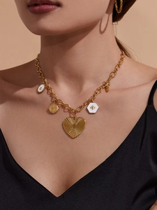 Détail du collier à grosse chaîne dorée avec pendentif cœur et breloques abeille