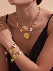 Gros plan d'un ensemble de bijoux dorés avec pendentifs cœur et abeille