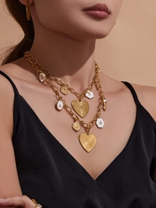Vue détaillée de colliers superposés avec pendentifs cœur et pièces en or sur mannequin