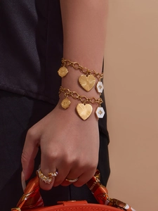 Détail du bracelet doré avec charm abeille émaillé et pendentifs cœur et pièces