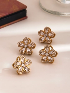 Dettaglio di orecchini placcati oro 18K con fiore a cinque petali in zircone lucido