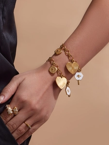 Gros plan d'un bracelet doré avec pendentifs cœur et abeille et des bagues assorties