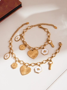 Détail d'un bracelet doré à breloques avec pendentifs cœur, abeille et clé sur fond neutre