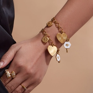 Bracelet à breloques cœur doré et bague papillon sur mannequin avec manche en soie noire